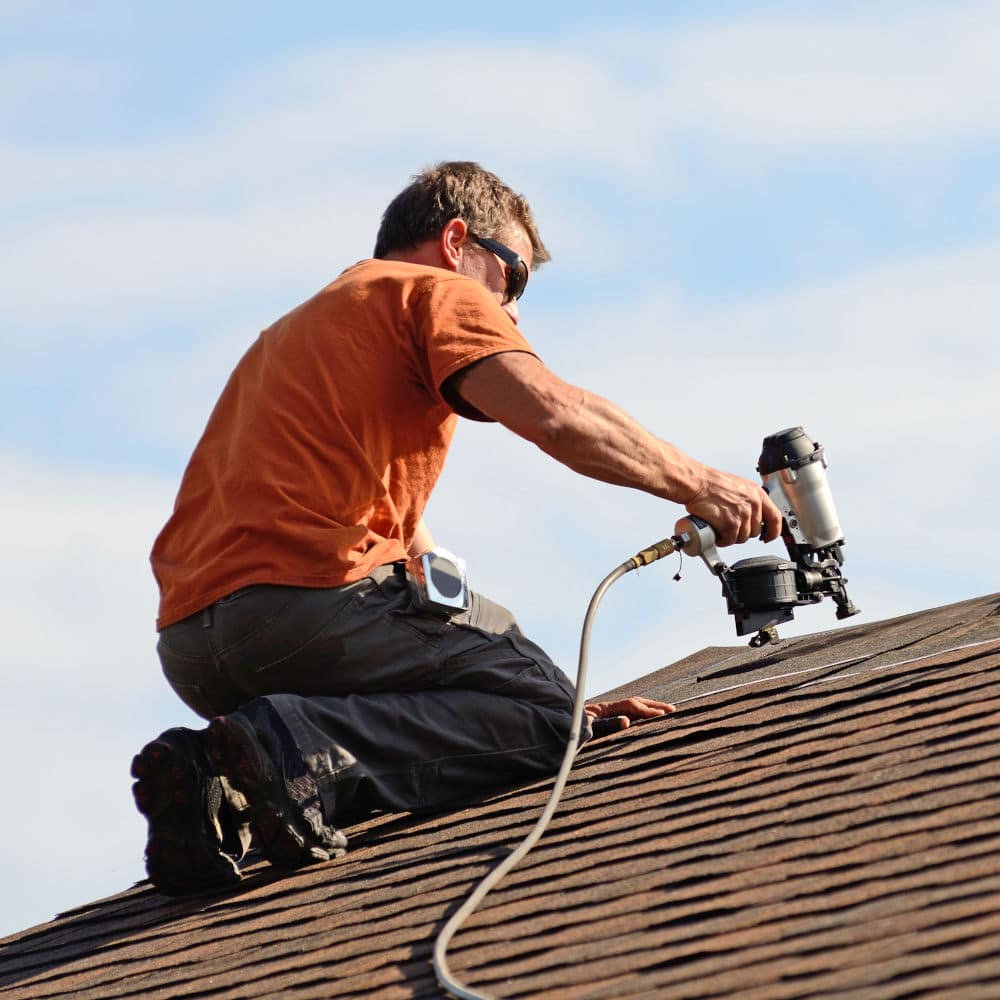 Building contractor putting the asphalt roofing on a large commercial apartment building development